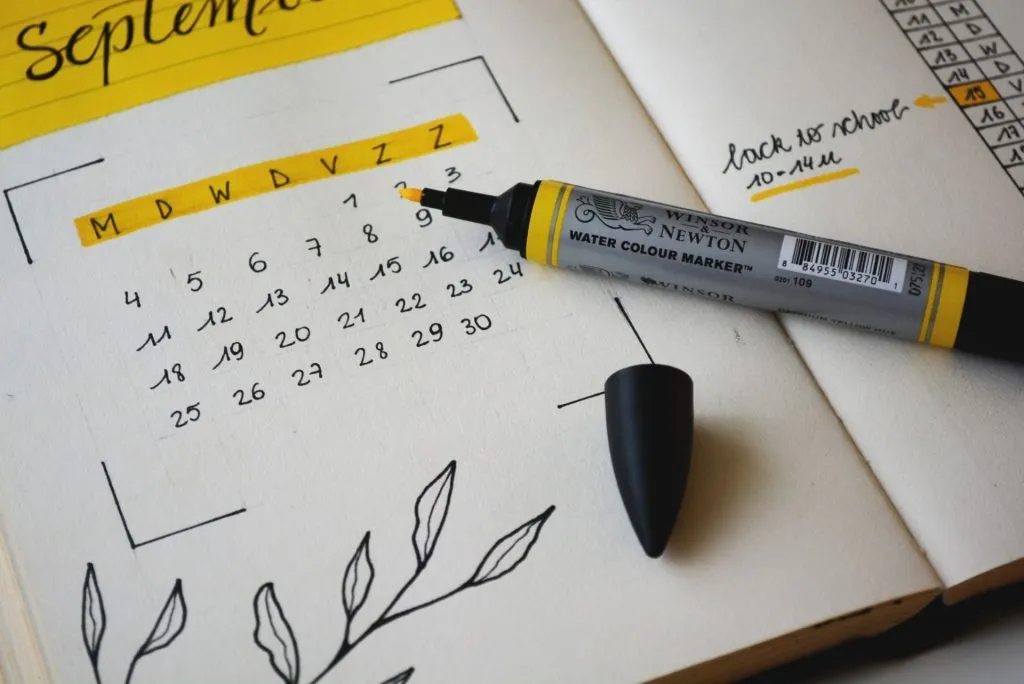A desk with a paper planner and phone, mapping out an Instagram posting schedule